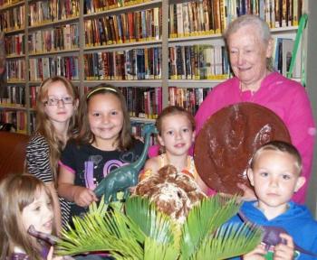 Jesse, Violet, Jasmine, Alexa and Braden stand with Georgie Thompson, who is holding a cast of a dinosaur footprint. Courtesy of Wiscasset Public Library